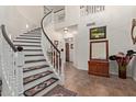 Bright foyer with winding staircase, tile floors and stylish decorations at 7242 W Aurora Dr, Glendale, AZ 85308