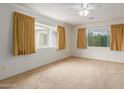 Spacious bedroom with carpet flooring, ceiling fan, and abundant natural light from large windows at 8337 E Desert Trl, Mesa, AZ 85208