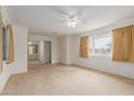Bright living room featuring carpet flooring, a ceiling fan, and large windows at 8337 E Desert Trl, Mesa, AZ 85208