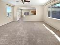 Bright, open-concept living room featuring large windows and neutral carpeting at 15369 W Wethersfield Rd, Surprise, AZ 85379