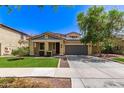 Charming home with two-car garage, covered porch, desert landscaping, and a lush green lawn at 20709 W Delaney Dr, Buckeye, AZ 85396