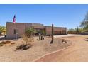 Exterior of a modern desert home featuring desert landscaping, an American flag and a circular driveway at 3019 W Trail Dr, Phoenix, AZ 85086