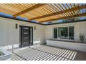 Modern entryway with black trimmed front door and wood pergola at 47 Spur Cir, Scottsdale, AZ 85251
