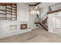 Living room with whitewashed brick fireplace, open staircase, and vaulted ceiling at 635 N Yale Dr, Gilbert, AZ 85234