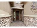 Warm entryway features beautiful stone accents and a welcoming wooden door with decorative wreath at 12381 S 182Nd Dr, Goodyear, AZ 85338