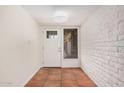 Bright entryway featuring tile flooring, a white front door, and a textured white brick accent wall at 1817 W Seldon Ln, Phoenix, AZ 85021