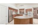 Well-lit kitchen showcasing stainless steel refrigerator, ample counter space and eat-in island at 18562 N Alamo Dr, Surprise, AZ 85374