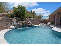 Tranquil pool with rock waterfall feature and cozy patio seating for relaxation and outdoor enjoyment at 28019 N 115 Pl, Scottsdale, AZ 85262