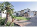 Home front yard featuring Palm trees, a circular flower bed, decorative rock and a two-story house at 3371 W Grandview Rd, Phoenix, AZ 85053