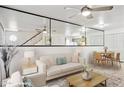 Bright and airy living room with mirrored accent wall, ceiling fan, and adjacent dining area at 510 N Alma School Rd # 139, Mesa, AZ 85201
