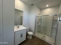 Full bathroom with an all glass shower, white vanity, and toilet at 7433 W Rovey Ave, Glendale, AZ 85303