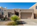 A tan home with xeriscaping and native plants, a stone facade, and an attached two-car garage at 10869 E Hedgehog Pl, Scottsdale, AZ 85262