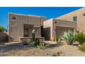 A tan home with xeriscaping and native plants, a stone facade, and an attached two-car garage at 10869 E Hedgehog Pl, Scottsdale, AZ 85262