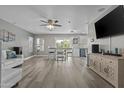 Open-concept living area with dining table, ceiling fan, wood-look floors, and view into kitchen at 11915 W Charter Oak Rd, El Mirage, AZ 85335
