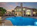 Gorgeous backyard with a sparkling blue pool, covered patio, and lush landscaping with a peek of sunset colors at 15215 S 20Th Pl, Phoenix, AZ 85048