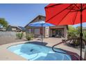 Outdoor view of the pool area and brick patio enhanced by red and blue shade umbrellas at 1813 N Lewis Pl, Casa Grande, AZ 85122