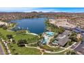 Expansive aerial view showcases a community lake, swimming pools, lush green spaces, and mountain views at 18371 W Sunrise Dr, Goodyear, AZ 85338