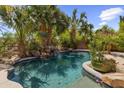 Inviting backyard pool with rock waterfall feature, surrounded by lush tropical landscaping and privacy walls at 285 W Goldfinch Way, Chandler, AZ 85286