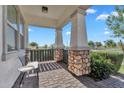 Covered porch with stone columns, brick flooring, and a cozy seating area at 3415 E Arabian Dr, Gilbert, AZ 85296