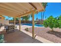 Covered patio offering an outdoor dining space with views of the sparkling pool and lush backyard at 4815 E Everett Dr, Scottsdale, AZ 85254