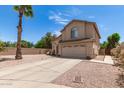Charming home with gravel landscaping, palm tree, long driveway leading to a two-car garage, and a sunny sky at 6657 W Aurora Dr, Glendale, AZ 85308