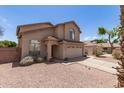 A tan home with well-kept gravel landscaping, a two-car garage, and a charming arched entryway at 6657 W Aurora Dr, Glendale, AZ 85308