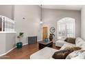 Bright living room with hardwood floors, staircase, vaulted ceilings, and a comfortable sectional sofa at 6657 W Aurora Dr, Glendale, AZ 85308