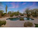 Backyard oasis with a beautiful pool, waterfall feature, and lush desert landscaping at 6672 E Horned Owl Trl, Scottsdale, AZ 85266