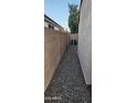 Narrow side yard with gravel, enclosed by block fencing providing privacy at 6722 W Shannon St, Chandler, AZ 85226