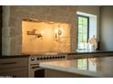 Detailed view of the kitchen range and stone feature wall, with a black framed window at 8910 E Topeka Dr, Scottsdale, AZ 85255