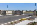 Gated Community entrance featuring well-maintained landscaping, stone pillars, black iron gates, and a playground in the background at 17417 W Eva St, Waddell, AZ 85355