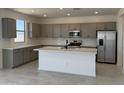 Modern kitchen with gray cabinets, stainless steel appliances, an island, and stylish tile backsplash at 22382 W Monona Ln, Surprise, AZ 85387
