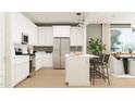 Modern kitchen featuring sleek white cabinets, stainless steel appliances, and an island with seating at 25453 N 176Th Ave, Surprise, AZ 85387