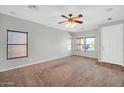 Spacious living room featuring neutral walls, multiple windows, a ceiling fan, and carpeted floors at 6330 W Constance Way, Laveen, AZ 85339