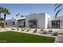 Modern home featuring a white brick facade, dark-framed windows, and a minimalist landscape design with desert plants at 7001 E Joan De Arc Ave, Scottsdale, AZ 85254