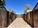 A long walkway between fences offering a glimpse of the clear blue sky above a fenced backyard at 12445 N 21St Ave # 4, Phoenix, AZ 85029