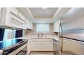 A well-lit kitchen featuring stainless steel appliances, white cabinetry, countertops, and tiled backsplash at 12445 N 21St Ave # 4, Phoenix, AZ 85029