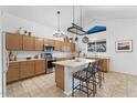 Bright kitchen featuring wood cabinets, modern appliances, an island with seating, and ample counter space at 12745 W Calavar Rd, El Mirage, AZ 85335