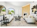 Open-concept living room with a modern fireplace, stylish seating, and a large arched window at 14123 W Greentree S Dr, Litchfield Park, AZ 85340