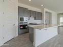 Modern kitchen featuring gray cabinets, white quartz countertops, and stainless steel appliances at 16355 W Desert Mirage Dr, Surprise, AZ 85388