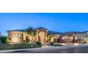 Impressive home exterior showcasing a stone facade, tile roof, and manicured landscaping at dusk at 16432 S Mountain Stone Trl, Phoenix, AZ 85048