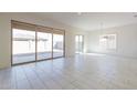 Bright living room featuring large sliding glass doors and neutral tile flooring at 18950 W Ocotillo Rd, Waddell, AZ 85355
