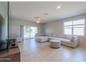 Spacious living room with tile floors, large sectional sofa, and sliding glass doors to backyard at 36522 W Santa Monica Ave, Maricopa, AZ 85138