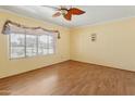 Bright bedroom with wood laminate flooring, yellow walls, and a leafy ceiling fan at 3836 W Desert Cove Ave, Phoenix, AZ 85029