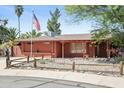 Inviting single-story home with a red brick exterior, desert landscaping, and an American flag at 3836 W Desert Cove Ave, Phoenix, AZ 85029