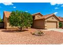 Single-story home featuring desert landscaping with a lush tree, providing shade and curb appeal at 3971 N 151St Ln, Goodyear, AZ 85395