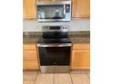Close-up of stainless steel oven and microwave with light wood cabinetry and tiled floor at 7176 W Blackhawk Dr, Glendale, AZ 85308