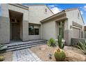 Desert landscaping with a stone paver walkway leads to the front door of this tan single-story home at 7673 E Sands Dr, Scottsdale, AZ 85255
