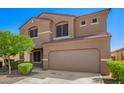 Charming two-story home featuring tan stucco, a two-car garage, manicured landscaping, and a blue sky at 8879 W Cameron Dr, Peoria, AZ 85345