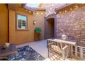 A cozy covered patio with a dining set, comfortable seating, decor, and stone accents at 10402 E Starion Ave, Mesa, AZ 85212